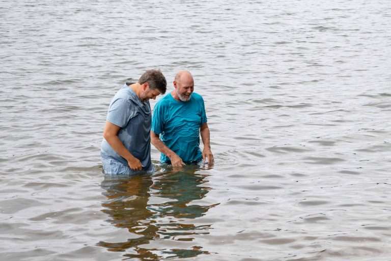 Rev. Thomas with man baptizing in West Point Lake at Church on the Hooch